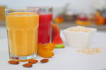 Glasses with tasty smoothie and fruits on kitchen table