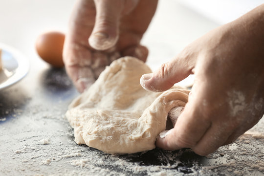 Male hands kneading fresh dough on table