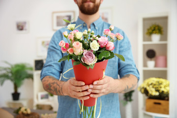 Close up view of tattooed florist holding paper cone with beautiful bouquet