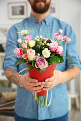 Close up view of tattooed florist holding paper cone with beautiful bouquet