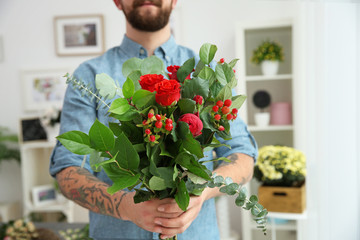 Close up view of tattooed florist holding beautiful bouquet