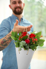 Closeup view of tattooed florist holding beautiful bouquet in paper cone
