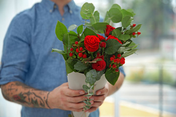 Close up view of tattooed florist holding beautiful bouquet in paper cone