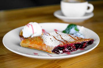 Plate with delicious dessert on wooden table at restaurant