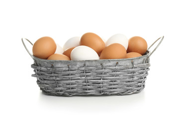 Basket with raw eggs on white background