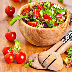 Mixed lettuce salad with cherry tomatoes in olive wood bowl
