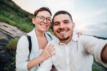 Beautiful young couple relaxing in the mountains and makes selfie.