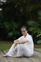 Mature man sitting outdoors in garden, looking at camera