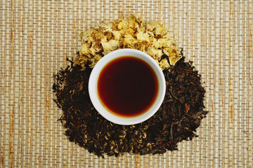Chinese teacup and pile of loose tea leaves, directly above