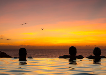Infinity edge pool with sea underneath sunset