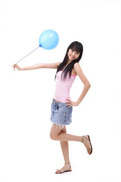 Young woman holding a blue balloon, standing on one leg