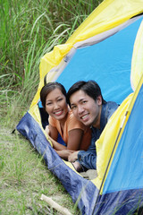Couple lying in tent, looking at camera