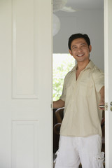 Man at home, standing at doorway, smiling