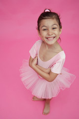Young girl in ballet outfit, arms crossed, smiling
