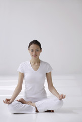 Woman sitting cross legged on floor, meditating, eyes closed
