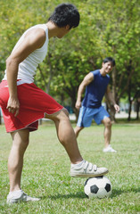 Two men playing soccer in park