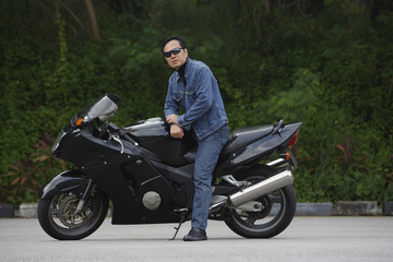 Fototapeta na wymiar Mature man sitting on motorcycle, wearing sunglasses