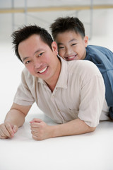 Father lying on floor, son lying on top of him, portrait