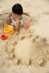 Young boy on beach building sand castle