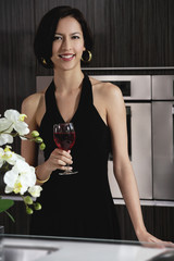A woman smiles at the camera holding a glass of red wine