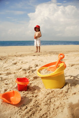 Young boy on beach, beach bucket and toys in foreground