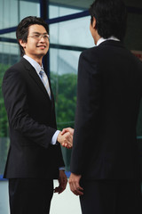 Two men wearing suits shake hands