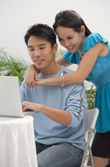 Young woman leaning on shoulder of man at the computer