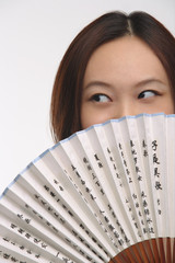 Young woman with fan looking sideways