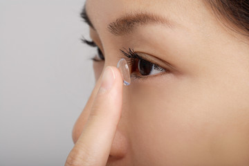 A young woman puts a contact lens in