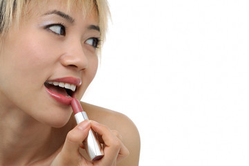 A young woman applies lipstick