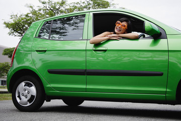 A young woman drives a green car