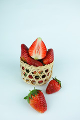 Fresh strawberries in a wooden basket on white background.