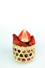 Fresh strawberries in a wooden basket on white background.