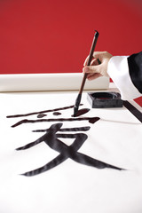 Woman writing Chinese calligraphy "Love"