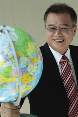 A man in suit holds a globe