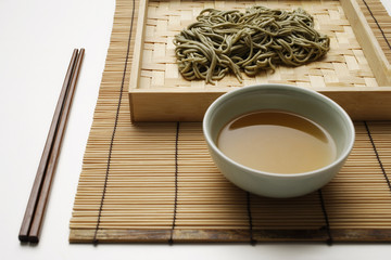 cooked soba noodles with sauce on bamboo tray and chopstick setting