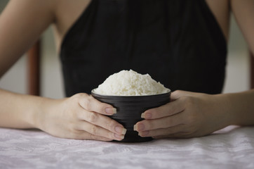 Young woman holding bowl of rice with both hands