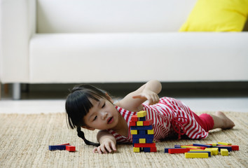 A small girl plays with blocks on the floor