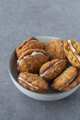 Individual mini carrot cake cookies in a white bowl. Gray background. Copy space. 