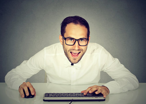 young crazy looking businessman with glasses typing on keyboard