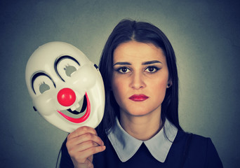 sad woman holding clown mask expressing cheerfulness happiness