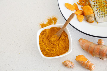 grated fresh turmeric root and turmeric powder, copy space background