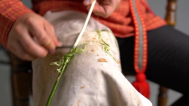 Crafts. View of boy cleans twig from bark