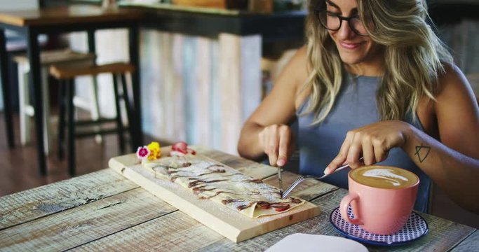 Young woman drinking coffee and eating crepes in cafe