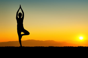 woman in a meditating yoga pose overlooking the beautiful sunset
