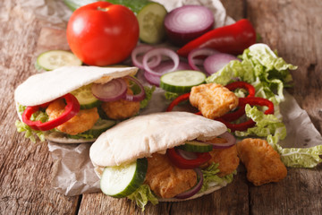 Tasty pita with chicken nuggets, cucumber, nappa cabbage, onion and bell peppers closeup. horizontal