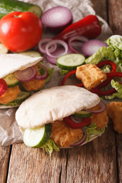 Tasty pita with chicken nuggets, cucumber, nappa cabbage, onion and bell peppers closeup. Vertical