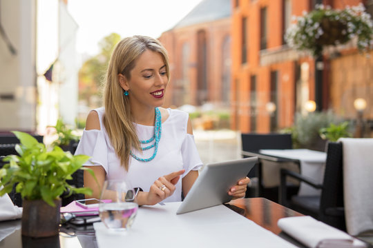 Woman sitting in outdoor cafe and using tablet