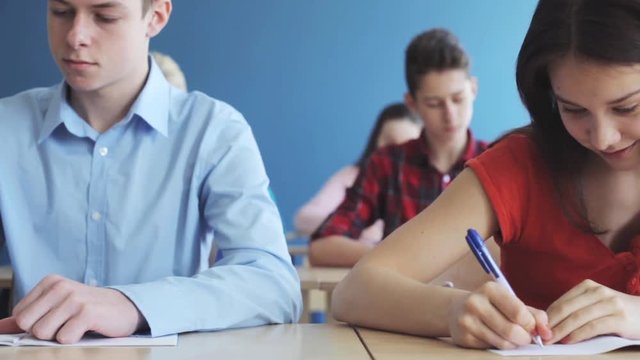 students with notebooks writing test at school