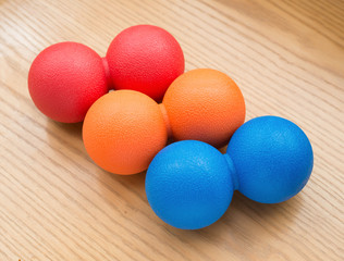 red and orange and blue small massage balls on a wood table
